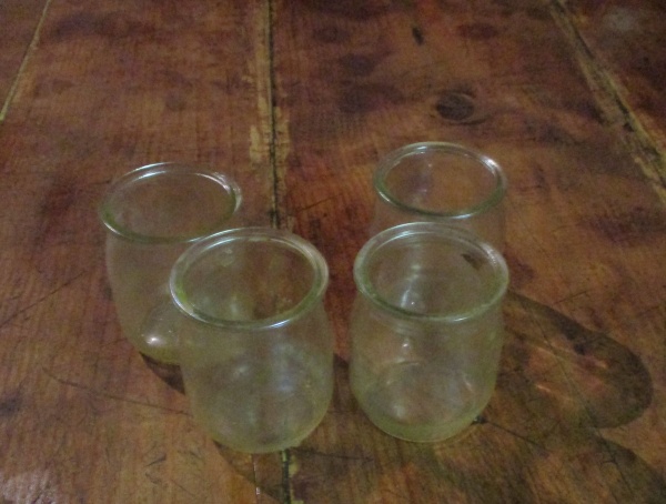 quatre pots de yaourt en verre sales sur une table en bois